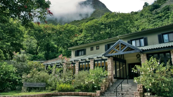 Belmond Sanctuary Lodge, hotel de luxo na entrada de Machu Picchu, cercado por montanhas verdes e floresta nublada.
