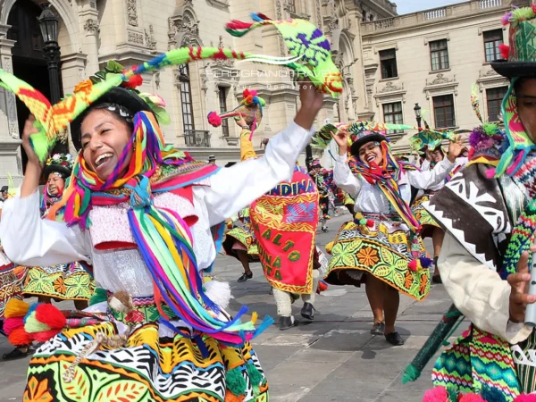 Dançarinos de comparsa com trajes andinos coloridos durante o Carnaval de Ayacucho, no Peru, apresentando danças folclóricas em uma praça colonial histórica.