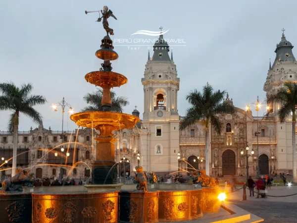 Fonte iluminada na Plaza Mayor de Lima ao entardecer, com a Catedral de Lima e palmeiras ao fundo no Centro Histórico