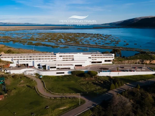 Hotel à beira do Lago Titicaca em Puno, Peru, vista aérea mostrando a propriedade cercada por áreas verdes e a paisagem do altiplano andino ao longo da margem do lago.
