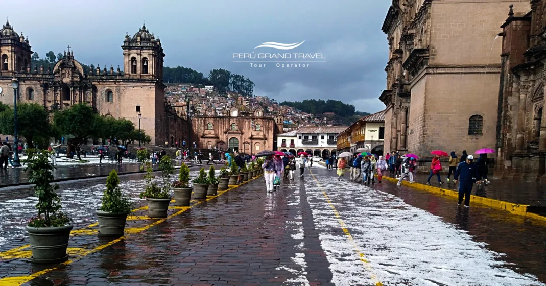 Plaza de Armas de Cusco com ruas molhadas, céu nublado e reflexos nas pedras após uma leve chuva. A imagem mostra a estação chuvosa, quando as paisagens ficam verdes, o ar mais fresco e a cidade mantém seu charme sob a garoa andina.