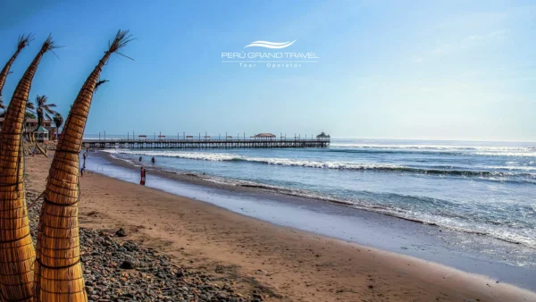 Praia de Huanchaco, perto de Trujillo, Peru, com os tradicionais caballitos de totora ao longo da costa arenosa do Pacífico