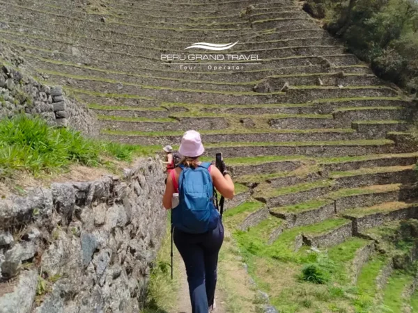 Viajante caminhando pela Trilha Inca Curta em Wiñay Wayna, cercado por terraços incas e natureza andina até Machu Picchu