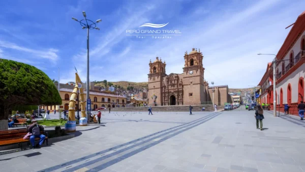 Vista ampla da Praça Principal de Puno “Plaza de Armas”, com a catedral ao fundo, prédios coloniais e um espaço aberto para pedestres