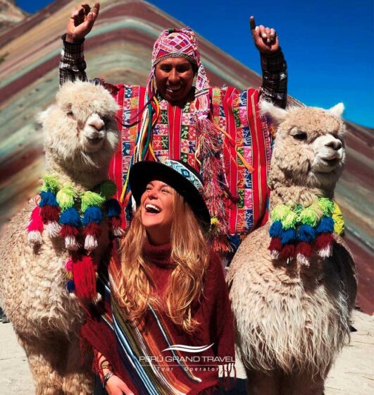 Turista sorridente ao lado de lhamas e um morador local na Montanha 7 cores, Cusco, Peru, experiência cultural andina
