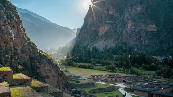 Sítio arqueológico de Ollantaytambo em Cusco no Vale Sagrado com uma vista cheia de cores verdes e o sol nascendo sobre a montanha