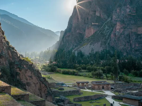 Sítio arqueológico de Ollantaytambo em Cusco no Vale Sagrado com uma vista cheia de cores verdes e o sol nascendo sobre a montanha
